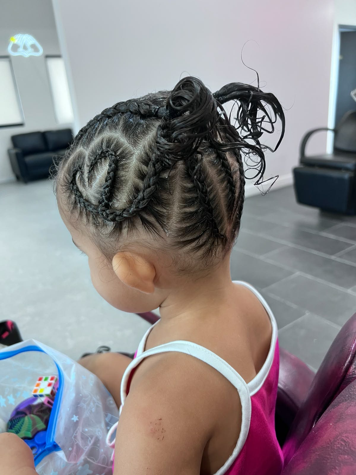 Heart braid design with a curly bun on a toddler
